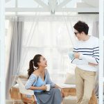 Young Vietnamese couple joking and drinking coffee